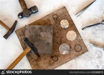 Top view jewelry maker workbench with tools on table. Equipment and tools of a goldsmith on wooden working desk inside a workshop.