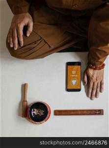 top view man meditating with singing bowl smartphone