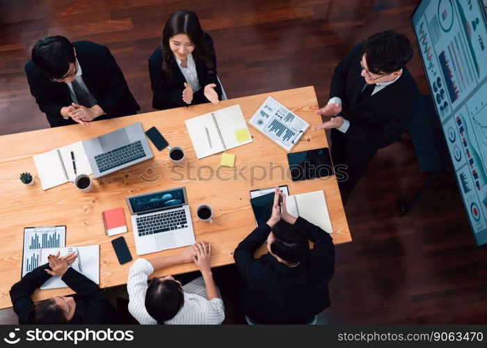 Top view manager or office worker give presentation in harmony conference room to business colleague, BI data dashboard on screen and pile of financial analyzed data reports on meeting table.. Top view business presentation at harmony conference room with colleagues.