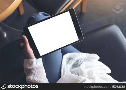 Top view mockup image of a woman sitting cross legged and holding black tablet pc with blank white desktop screen