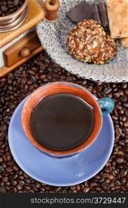 top view mug of coffee and roasted coffee beans with retro copper manual mill, biscuit, chocolate bars