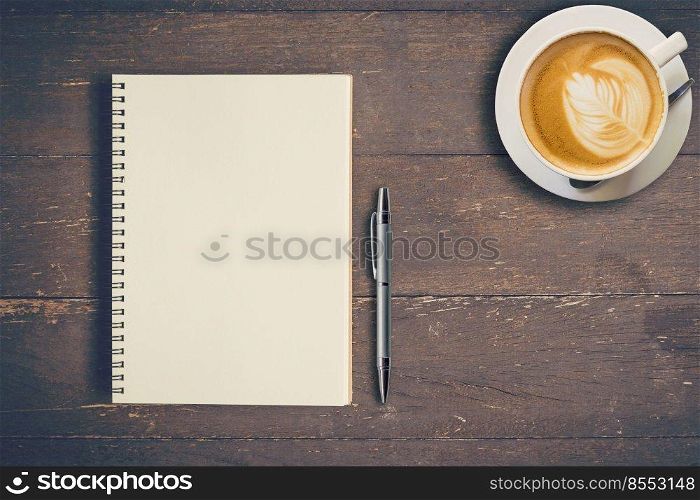 Top view notebook and pen with coffee cup on wood table, Vintage filter.