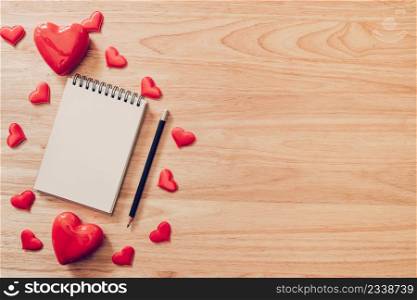 Top view notepad and red heart on wood background for valentine day with copy space.