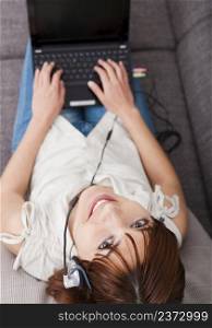 Top view of a beautiful young woman at home with a laptop and speaking over the internet with headphones