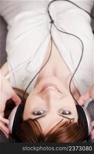 Top view of a beautiful young woman listening music with headphones