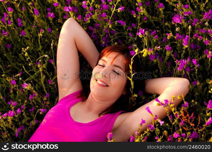 Top view of a beautiful young woman lying on a flowery meadow