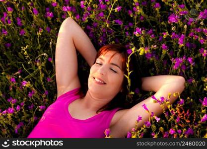 Top view of a beautiful young woman lying on a flowery meadow