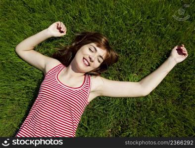 Top view of a beautiful young woman lying on a green meadow