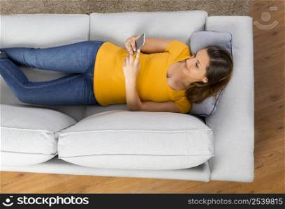 Top view of a beautiful young woman lying on a sofa and send text messages