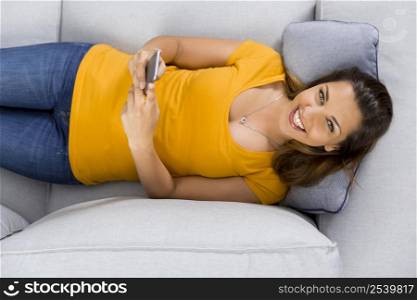 Top view of a beautiful young woman lying on a sofa and send text messages