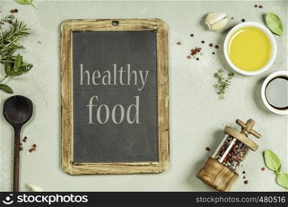 Top view of a blank chalk board for a wine list or menu with Olive oil, balsamic vinegar, pepper and herbs on concrete background - cooking ingredients -- top view. Healthy food vegan or diet nutrition concept.. Olive oil, balsamic vinegar, pepper and herbs
