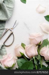 Top view of a bouquet of pink roses, scissors and fabric on a grey concrete background. Florist work place. Accessories for making bouquets and floral compositions.