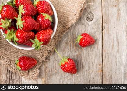 Top view of a bowl with strawberry on wooden background