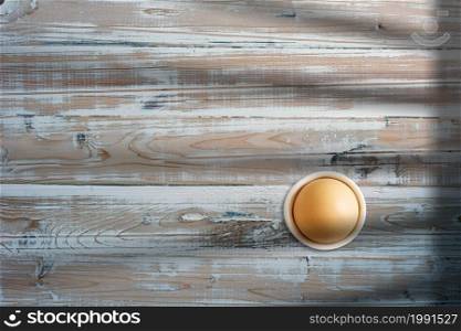 Top view of a chicken egg on the corner of a wooden table. added copy space for text.