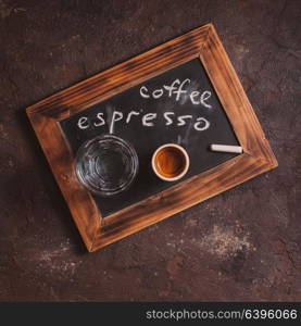 Top view of a cup of coffee and glass water on an old school slate with inscription. Coffee espresso for gourmet