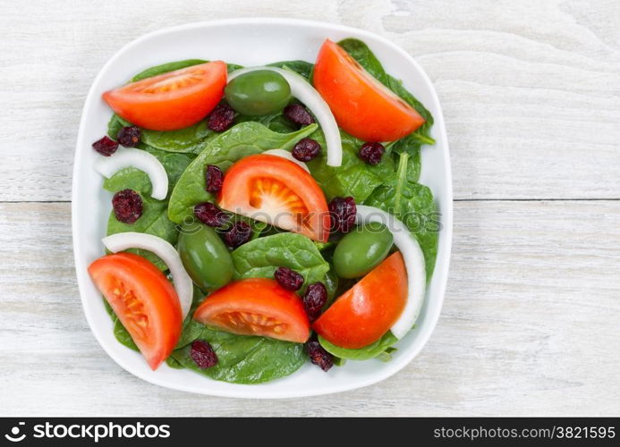 Top view of a freshly made salad, in white plate, on rustic white wood