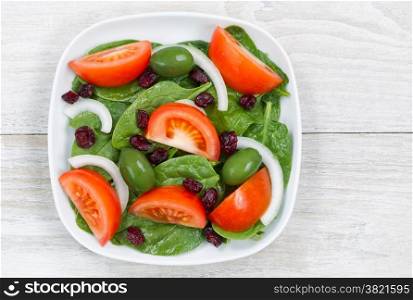 Top view of a freshly made salad, in white plate, on rustic white wood