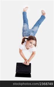 Top view of a little girl lying on floor working with a laptop
