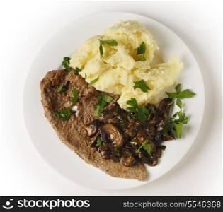 Top view of a meal of a fried veal escalope with sauteed mushrooms and mashed potatoes.