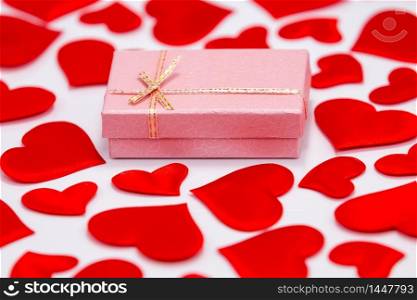 Top View of a Pink Gift Box Surrounded by Scattered Hearts on White Background. St. Valentines Day Concept.