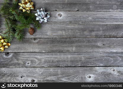 Top view of a single pine cone with fir branches and shiny gold and silver gift bows on aged wooden planks for a Merry Christmas