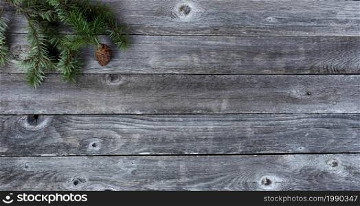 Top view of a single pine cone with fir branches on aged wooden planks for a Merry Christmas