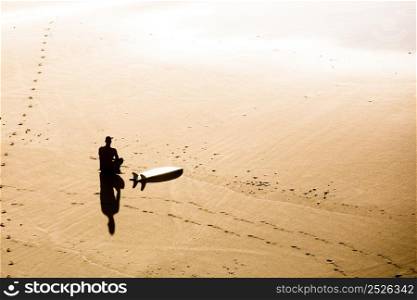 Top view of a surfer sitting on the beach