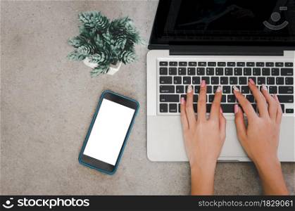Top view of a woman hand using a laptop computer keyboard and mobile phone mock up a blank screen.
