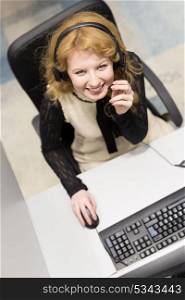 top view of a young smiling female call centre operator doing her job with a headset