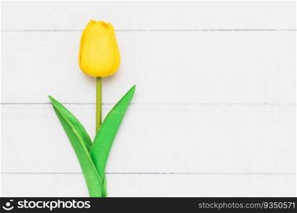 Top view of an artificial yellow tulip on white table background for nature decoration and springtime concept