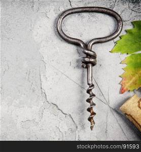 Top view of an old cork screw and grape leaf on gray concrete background with space for text. A horizontal design template for a tasting invitation or restaurant menu