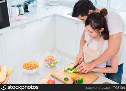 Top view of Asian lovers or couples cooking breakfast in the morning in kitchen room. Man teaching woman to slice vegetable and rice. Relationship and Family concept. Honeymoon and Holidays theme