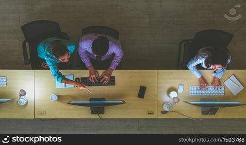 Top view of Asian Male customer care service working hard late in night shift at office,call center department,worker and overtime,team work with colleagues for success concept