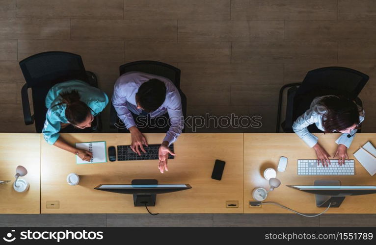 Top view of Asian Male customer care service working hard late in night shift at office,call center department,worker and overtime,team work with colleagues for success concept