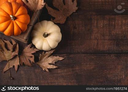 Top view of autumn leaves and mini pumpkins on wooden background