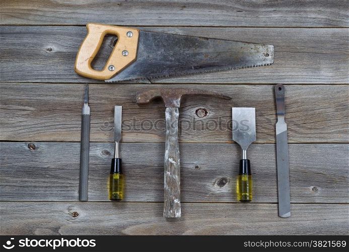 Top view of basic used tools on rustic wooden boards consisting of hammer, metal files, hand saw, and chisels.