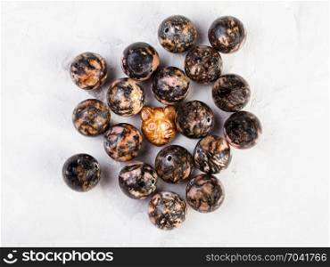 top view of beads from natural pink and black rhodonite mineral on gray concrete background