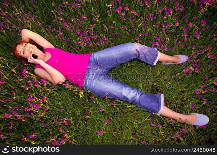 Top view of beautiful young woman lying on the nature and talking at cellphone 