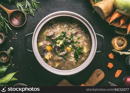 Top view of beef and cabbage soup or stew in cast iron cooking pot on dark background with ingredients and wooden spoon, top view. Healthy clean low-calorie food and eating concept