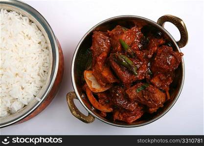 Top view of beef chilli curry in a traditional Indian metal bowl, with a bowl of rice