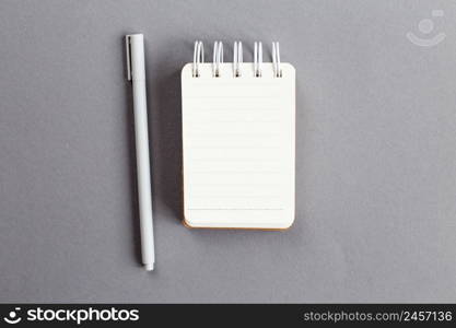 Top view of blank note paper with pen on gray background.. Top view of blank note paper with pen on gray background