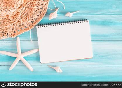 Top view of blank notebook on blue wood table, sea shells and starfish on a blue wooden background, Summer concept
