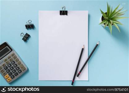 Top view of blank notebook, pen, calculator and green plant on blue office desk
