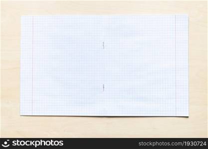 top view of blank open school notebook with squared sheets with margins on light brown wooden board