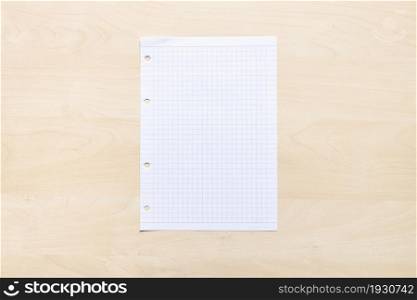 top view of blank sheet of squared paper on light brown wooden board