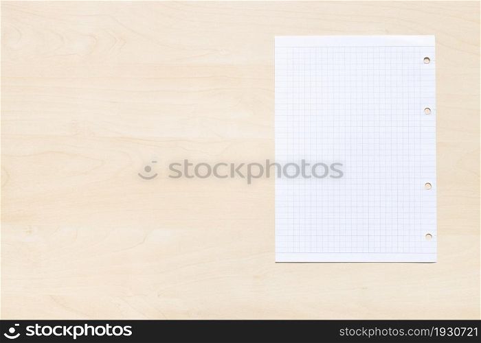 top view of blank sheet of squared paper on light brown wooden board with copyspace