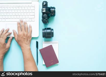 Top view of blogger's workspace desk with laptop, camera and passport. Travel concept