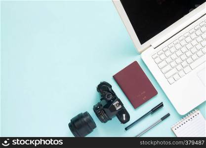 Top view of blogger's workspace desk with laptop, camera and passport. Travel concept