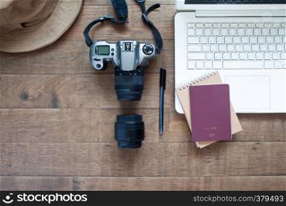 Top view of blogger's workspace desk with laptop, camera and passport. Travel concept