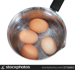 top view of boiling chicken eggs in metal pot on electric stove isolated on white background